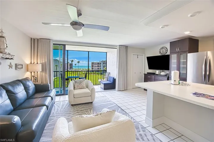 Living area with light tile patterned floors, floor to ceiling windows, and a ceiling fan