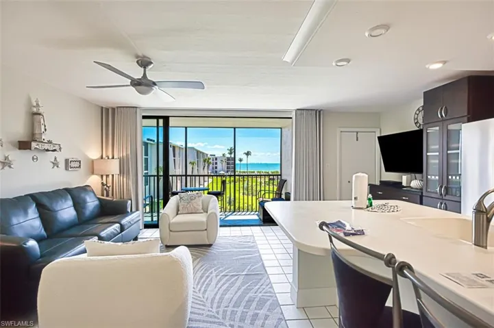 Living area with light tile patterned floors, a ceiling fan, and expansive windows