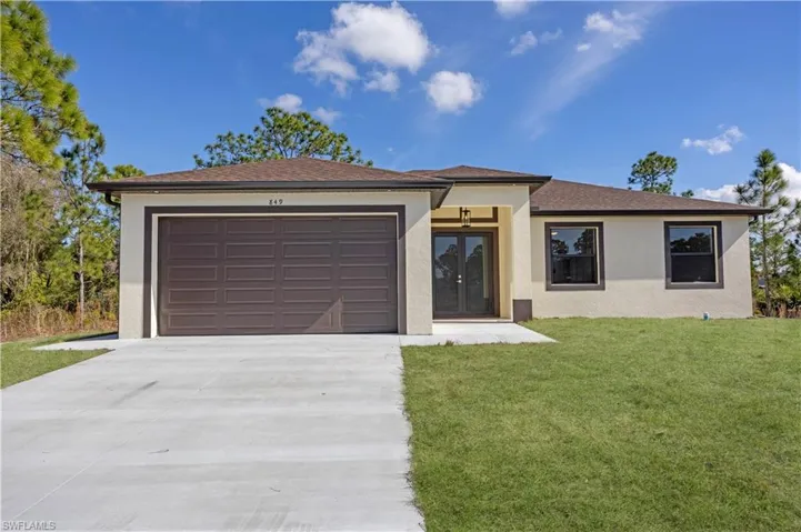 View of front of home featuring driveway, a front yard, stucco siding, french doors, and roof with shingles