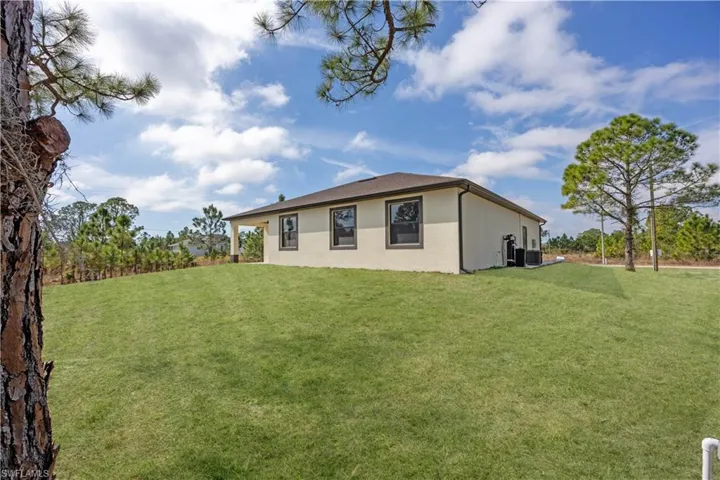 Back of house with a lawn and stucco siding