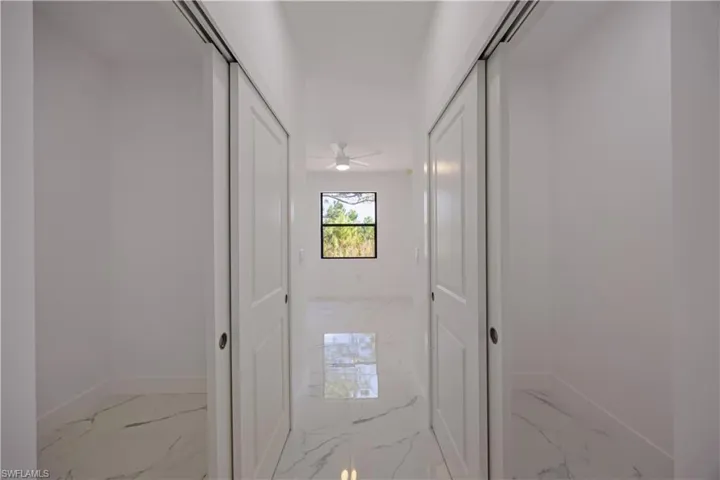 Doorway to outside featuring a ceiling fan and marble finish floors