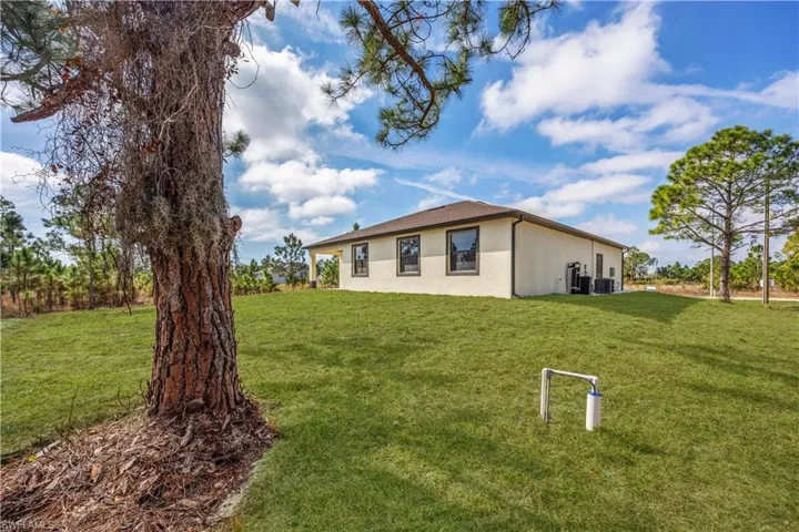 View of side of home with a lawn and stucco siding