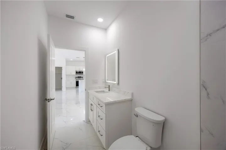 Bathroom with vanity, light marble finish flooring, and recessed lighting