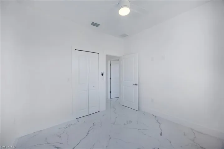 Unfurnished bedroom featuring light marble tile finish flooring, a closet, and a ceiling fan