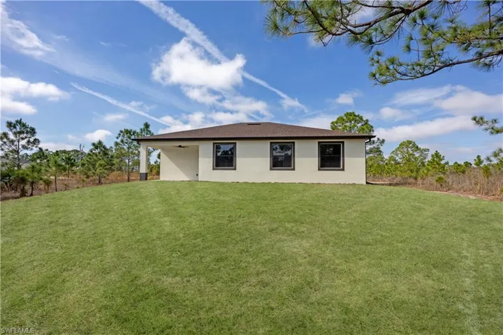 Rear view of house featuring a yard and stucco siding