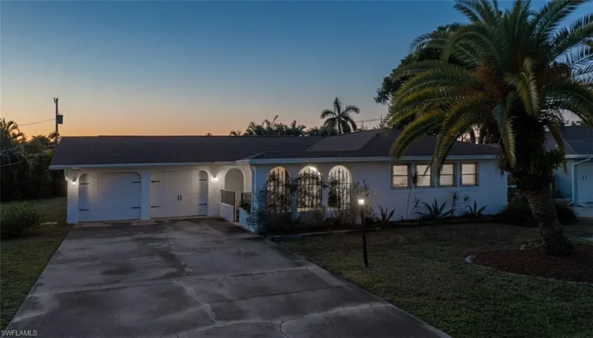View of front of home featuring concrete driveway, stucco siding, a front lawn, and a garage