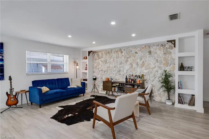 Living room with built in shelves, wood finish floors, and recessed lighting