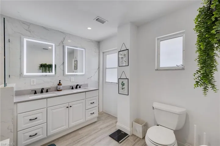Bathroom featuring double vanity, recessed lighting, and light wood-style floors
