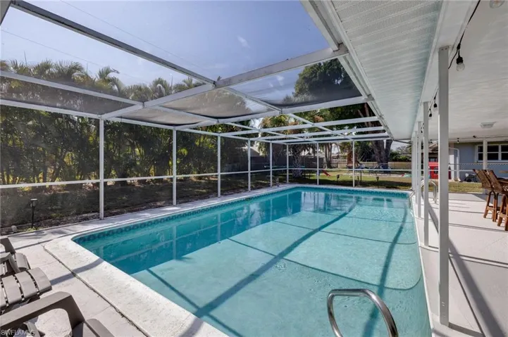 View of pool featuring glass enclosure, a patio, and a sunroom