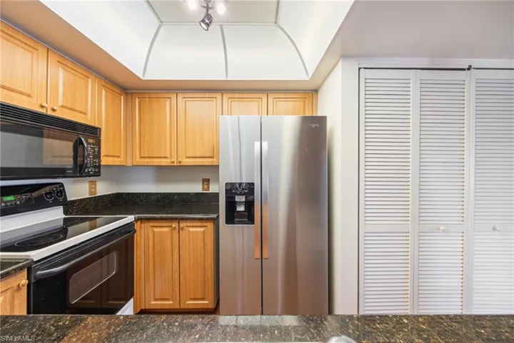 Kitchen with black appliances and dark stone counters