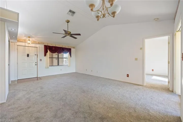 Unfurnished living room with hanging lights, light carpet, and a ceiling fan