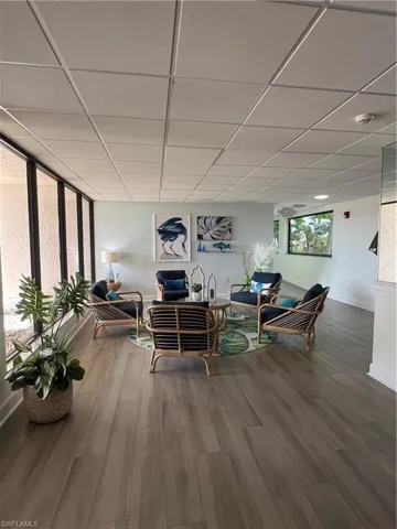 Living area with a paneled ceiling, wood finished floors, and baseboards