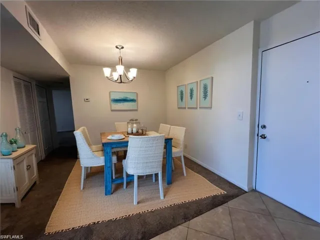 Dining space featuring a textured ceiling, visible vents, a chandelier, tile patterned floors, and baseboards