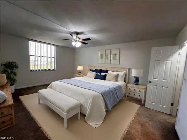 Bedroom featuring dark colored carpet, baseboards, and a ceiling fan