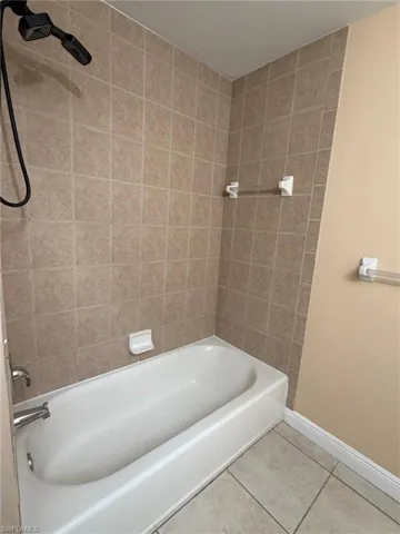 Bathroom with light tile patterned floors and tub / shower combination
