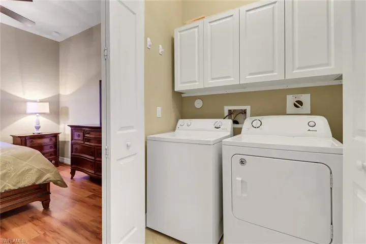 Laundry area with washing machine and dryer, light wood-type flooring, cabinet space, and a ceiling fan