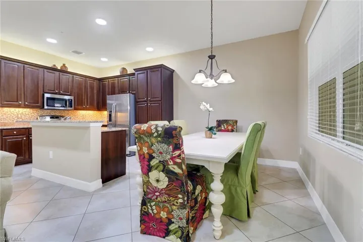 Kitchen with a kitchen island, dark wood finish cabinetry, light tile patterned flooring, a kitchen bar, and backsplash