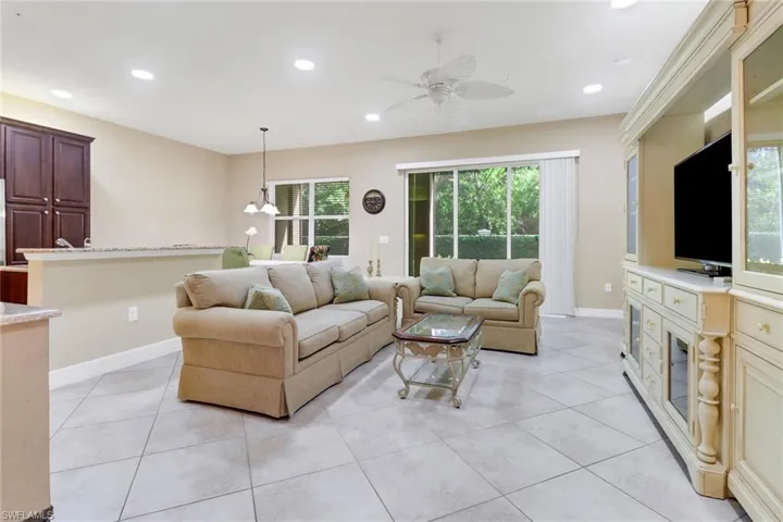 Living room featuring ceiling fan, light tile patterned flooring, and suspended lighting