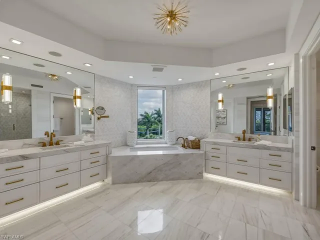 Bathroom featuring two vanities with quartz counters, a bath, a stall shower, and custom lighting