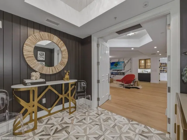 Hallway featuring a tray ceiling, marble flooring, wood accent wall, and recessed lighting