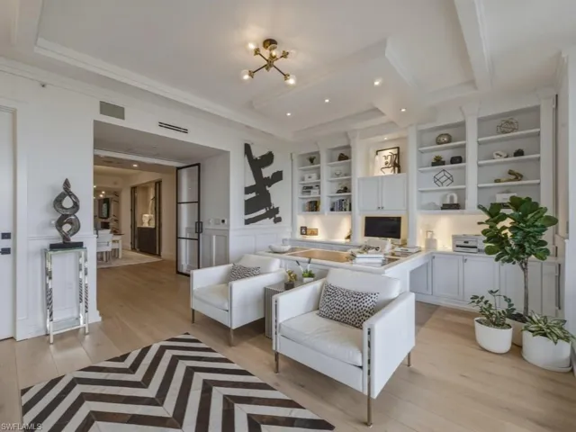 Living area featuring light wood-style flooring, crown molding, a decorative wall, wainscoting, and suspended lighting