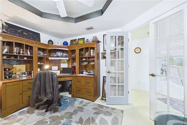 Home office with light colored carpet and a ceiling fan
