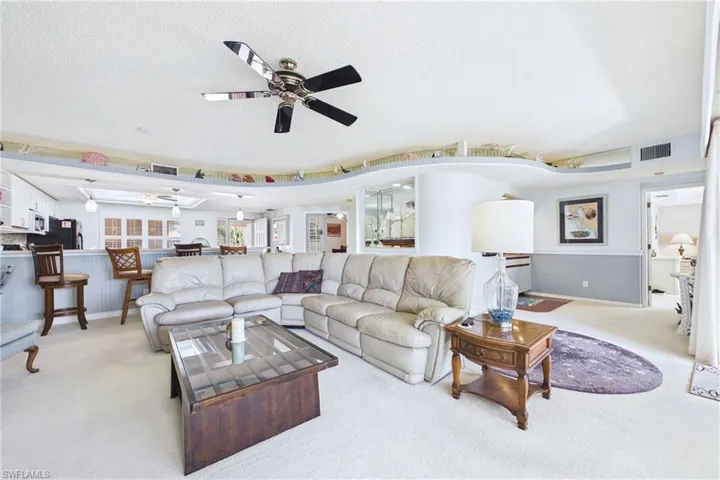 Living room with carpet, a textured ceiling, and ceiling fan