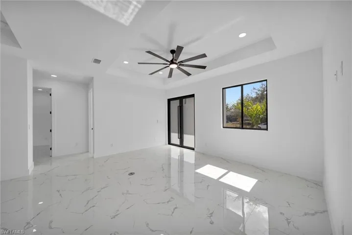 Spare room with light marble finish floors, a ceiling fan, recessed lighting, and a raised ceiling
