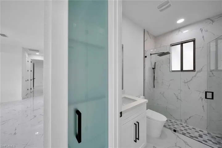 Full bathroom featuring a marble finish shower, vanity, recessed lighting, and light marble finish floors