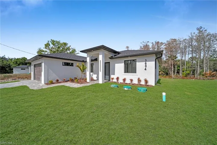 Prairie-style home with a front lawn, stucco siding, driveway, and an attached garage
