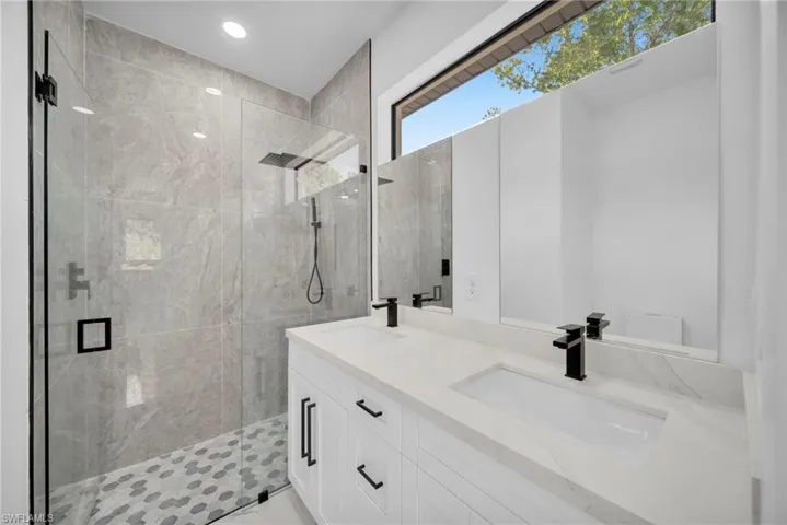 Bathroom featuring a stall shower, double vanity, and recessed lighting