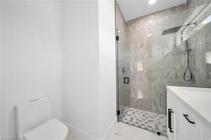 Full bathroom with a marble finish shower, vanity, and light marble finish floors