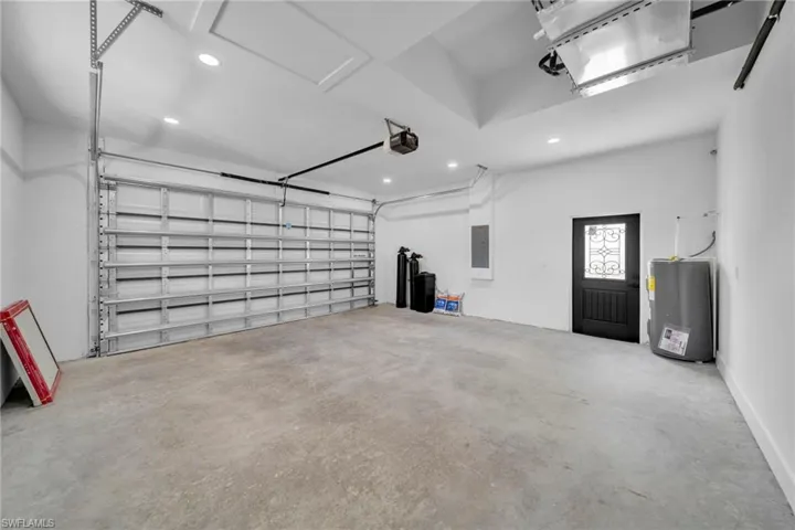 Garage with recessed lighting, water heater, electric panel, and a garage door opener