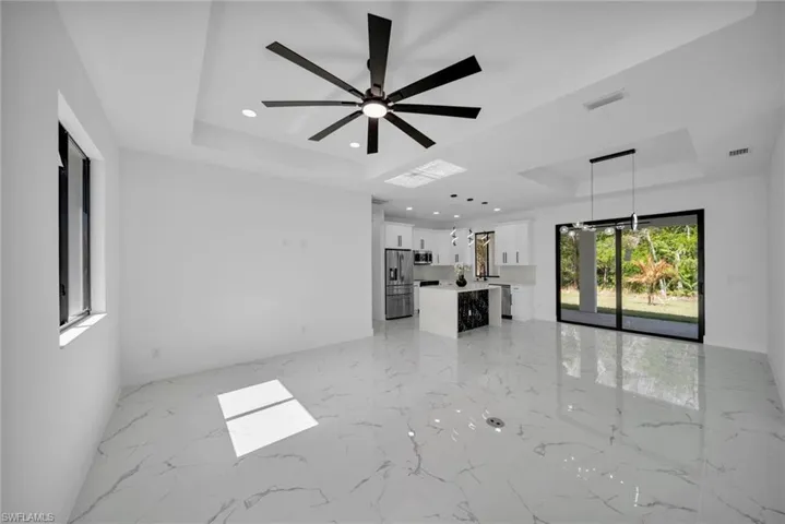 Unfurnished living room featuring a raised ceiling, recessed lighting, and ceiling fan