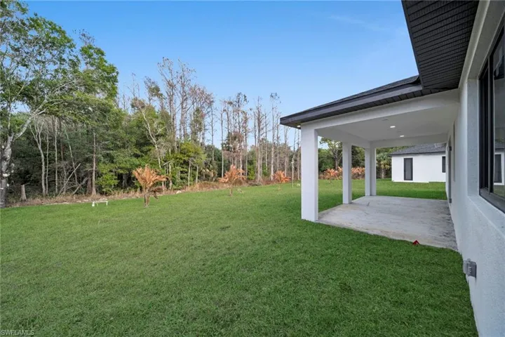 View of green lawn with a patio area
