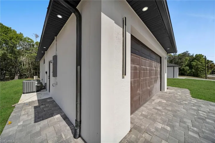 View of side of property featuring a yard, stucco siding, and decorative driveway