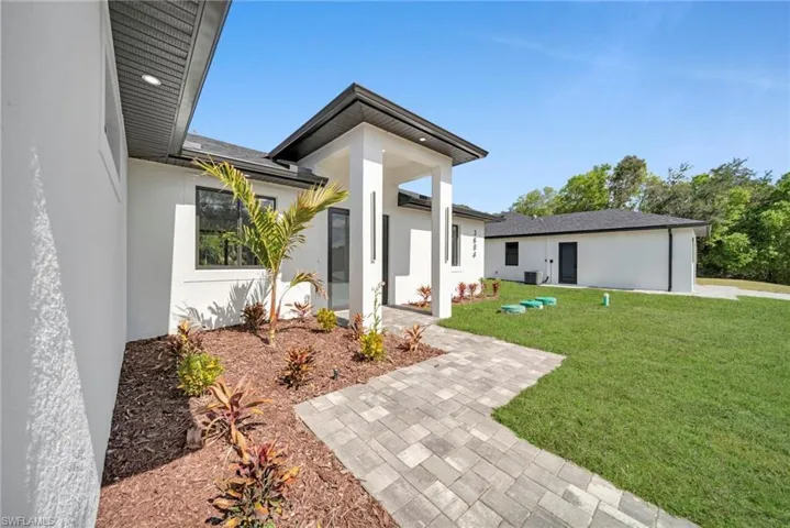 View of exterior entry with a yard and stucco siding