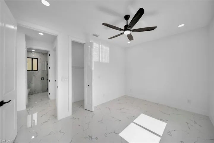 Unfurnished bedroom featuring recessed lighting, light marble finish flooring, a ceiling fan, and a spacious closet