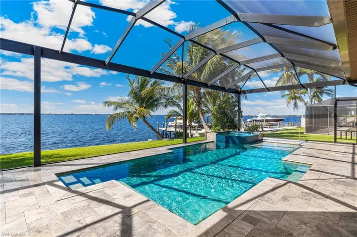 View of swimming pool with a patio, a water view, glass enclosure, and a pool with connected hot tub