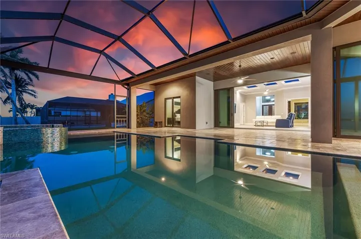 View of pool featuring exterior kitchen, a lanai, a patio, a pool with connected hot tub, and ceiling fan