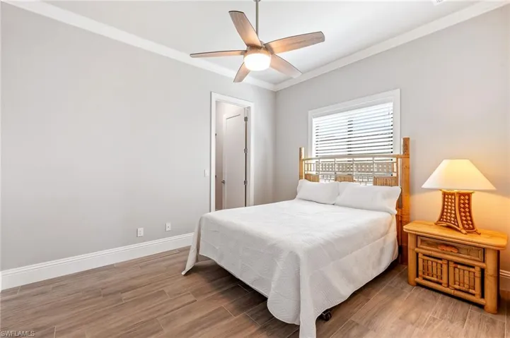 Bedroom with ornamental molding, wood finished floors, and ceiling fan