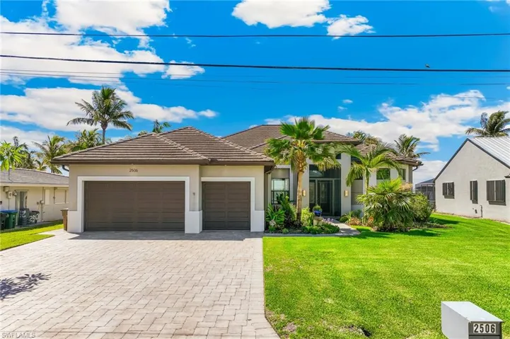 View of front of house with a garage, decorative driveway, a front lawn, and stucco siding