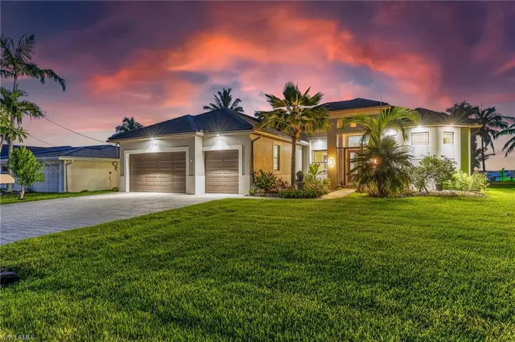 View of front of property featuring an attached garage, decorative driveway, a lawn, and stucco siding