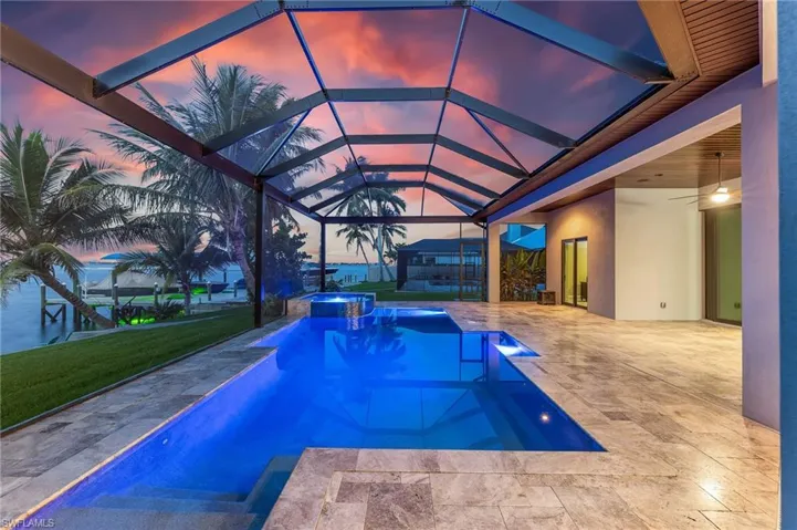 View of swimming pool featuring a patio area, a pool with connected hot tub, and glass enclosure
