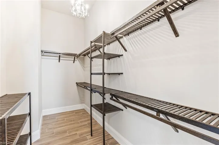 Walk in closet featuring wood finished floors, a chandelier, and heating unit
