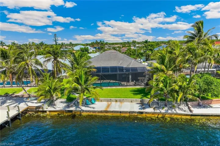 Back of house with a water view, glass enclosure, an outdoor pool, and a yard