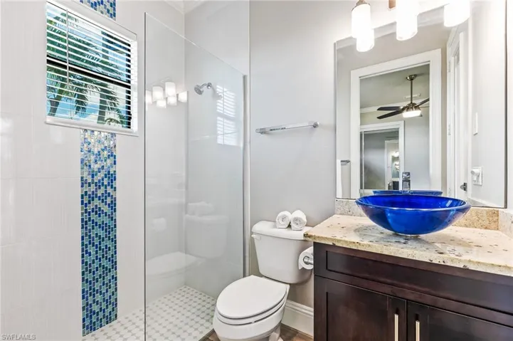 Bathroom with walk in shower, vanity, and ceiling fan