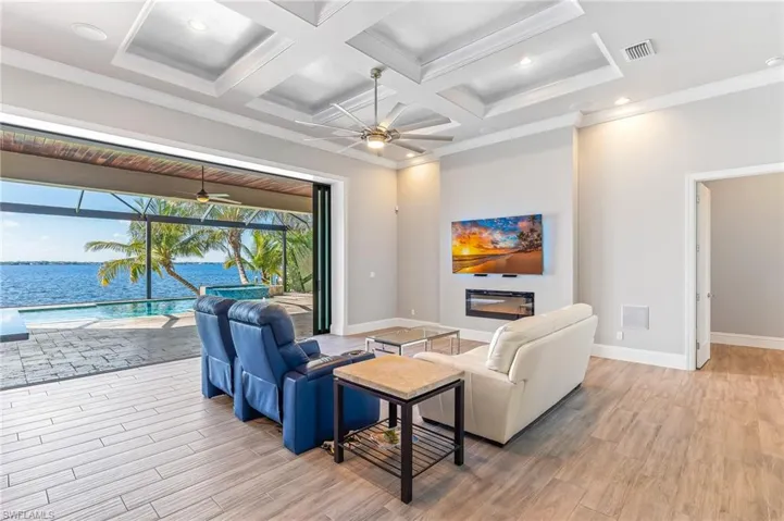 Living area featuring a sunroom, ceiling fan, light wood finished floors, beamed ceiling, and crown molding
