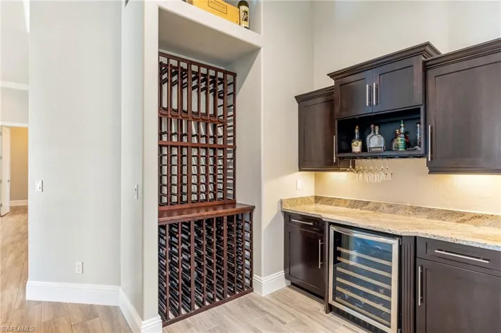 Wine area with beverage cooler, a dry bar, and light wood-type flooring
