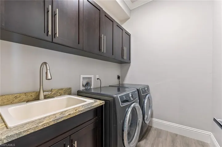 Washroom featuring separate washer and dryer, cabinet space, and wood finished floors